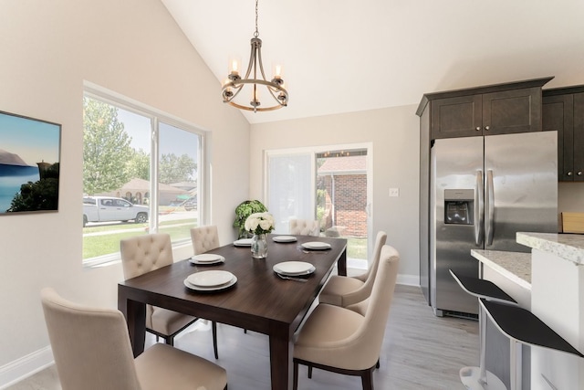 dining area with light wood-type flooring, lofted ceiling, plenty of natural light, and a notable chandelier