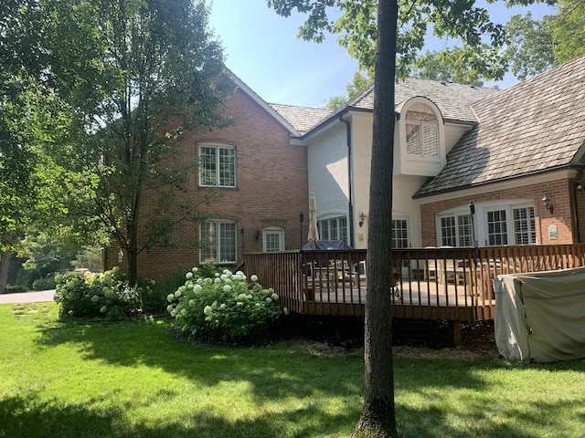 rear view of house with a wooden deck and a yard