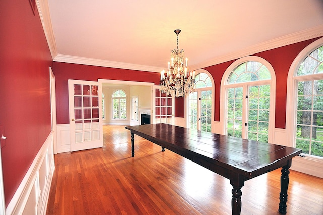 unfurnished dining area featuring a notable chandelier, wood-type flooring, ornamental molding, and french doors