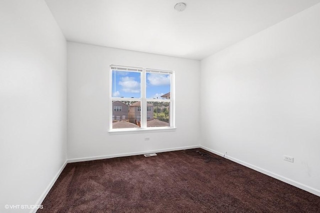 spare room with dark carpet