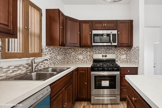 kitchen featuring stainless steel appliances, sink, light hardwood / wood-style flooring, and decorative backsplash