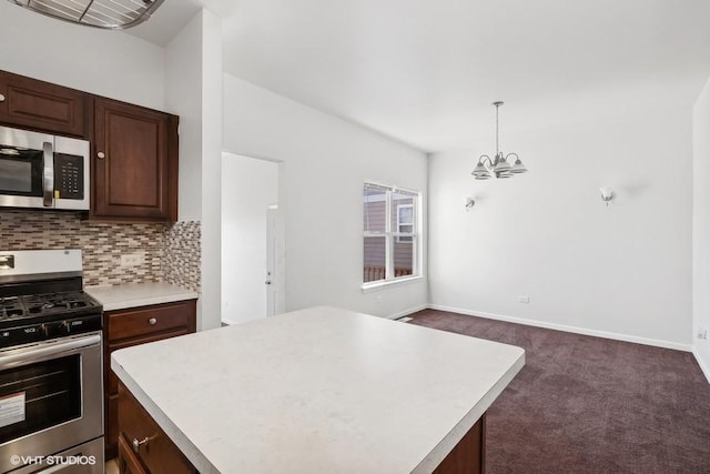 kitchen with a center island, appliances with stainless steel finishes, dark carpet, pendant lighting, and backsplash