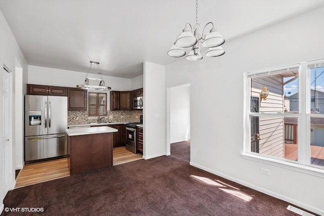 kitchen featuring appliances with stainless steel finishes, pendant lighting, decorative backsplash, carpet, and a center island