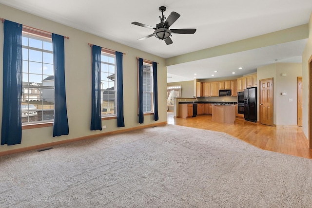 kitchen featuring a kitchen island, light colored carpet, ceiling fan, and black appliances