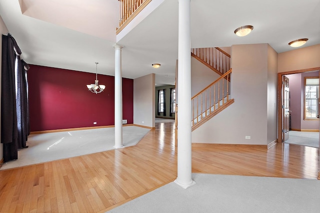 foyer entrance with a chandelier, decorative columns, hardwood / wood-style floors, and a high ceiling