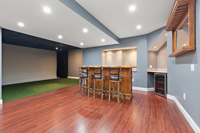 interior space featuring golf simulator, wine cooler, dark hardwood / wood-style flooring, and bar