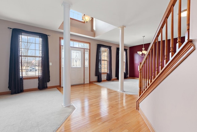 foyer with a notable chandelier, light wood-type flooring, and ornate columns