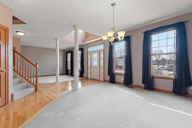 carpeted entrance foyer with decorative columns and a chandelier