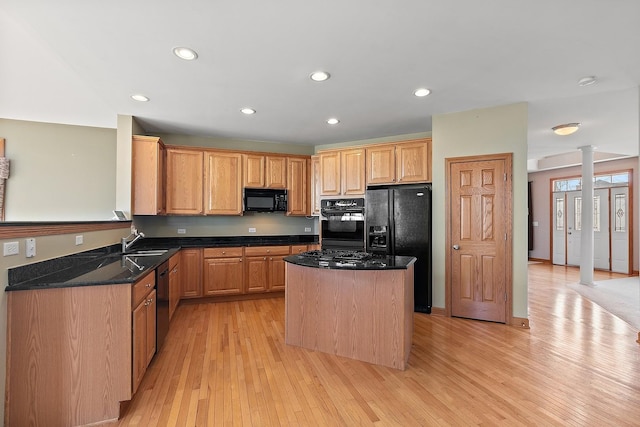 kitchen with ornate columns, sink, dark stone counters, a center island, and black appliances