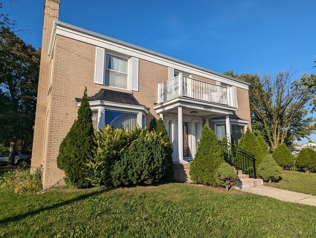 view of front of house with a balcony and a front yard