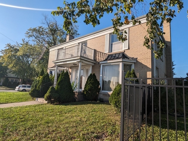 front of property with a balcony and a front lawn