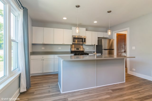 kitchen with white cabinetry, stainless steel appliances, sink, a center island with sink, and light hardwood / wood-style floors