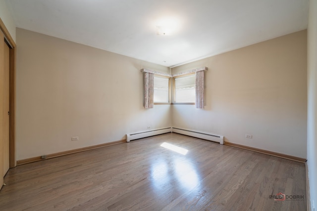 spare room featuring wood-type flooring and a baseboard radiator