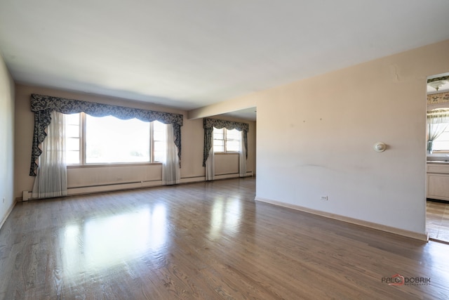 empty room with hardwood / wood-style flooring and a healthy amount of sunlight