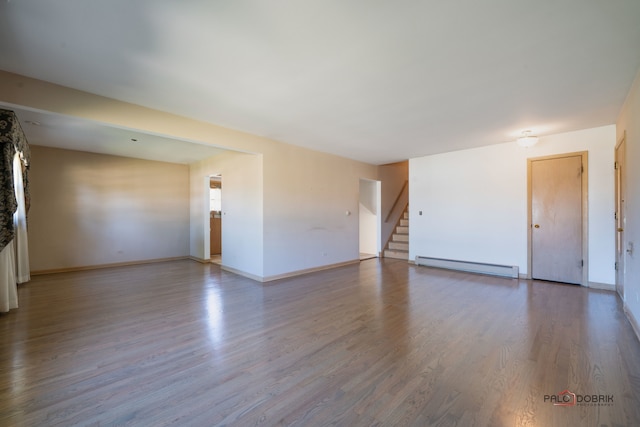 empty room featuring baseboard heating and hardwood / wood-style floors