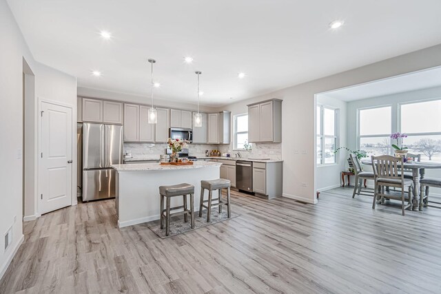 kitchen featuring light hardwood / wood-style flooring, stainless steel appliances, backsplash, gray cabinets, and a kitchen island