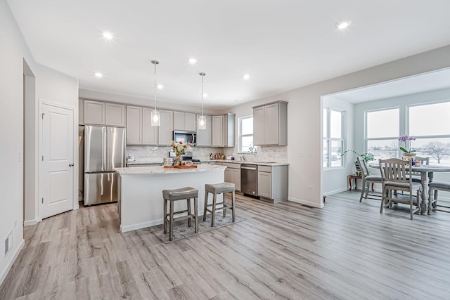 kitchen featuring decorative backsplash, a kitchen island, decorative light fixtures, stainless steel appliances, and gray cabinetry