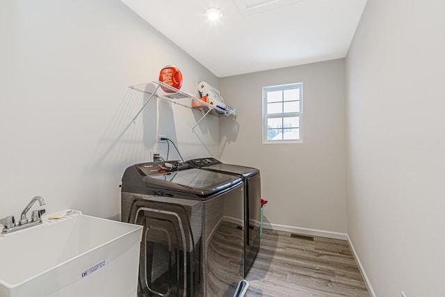 laundry area featuring laundry area, wood finished floors, a sink, baseboards, and washer and dryer