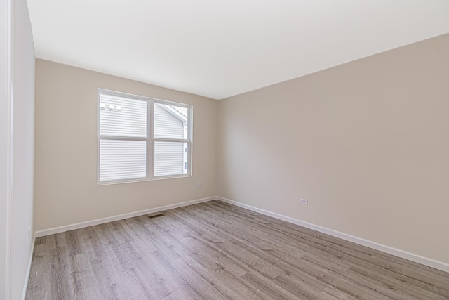 unfurnished room featuring light wood-style floors, visible vents, and baseboards