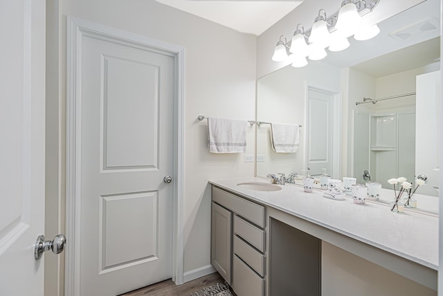 bathroom featuring a shower, wood finished floors, and vanity