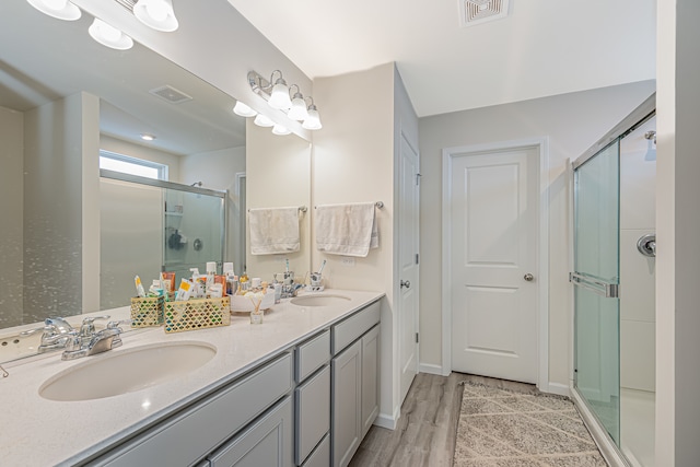 bathroom with a shower with door, double vanity, and wood-type flooring