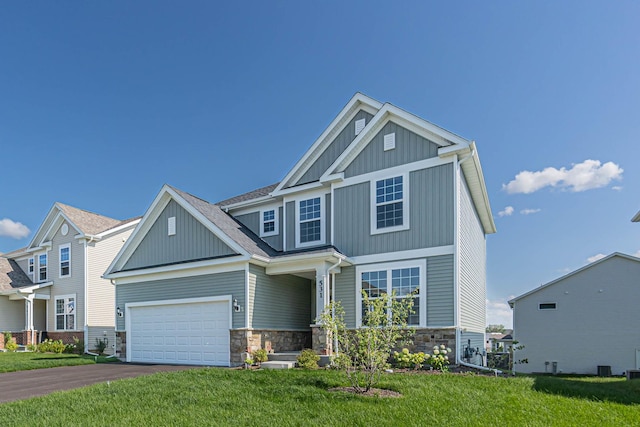 craftsman-style house with board and batten siding, a front yard, a garage, stone siding, and driveway