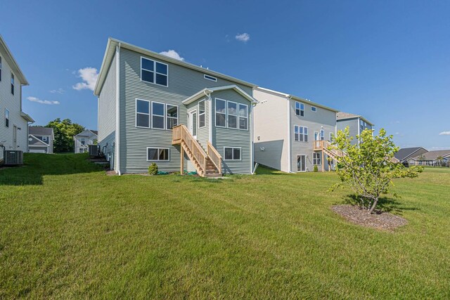 rear view of property with central air condition unit and a lawn