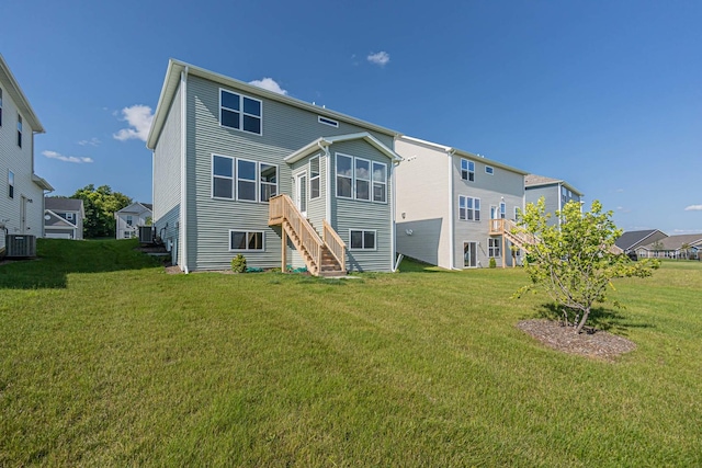 rear view of property featuring stairway, central AC, and a yard