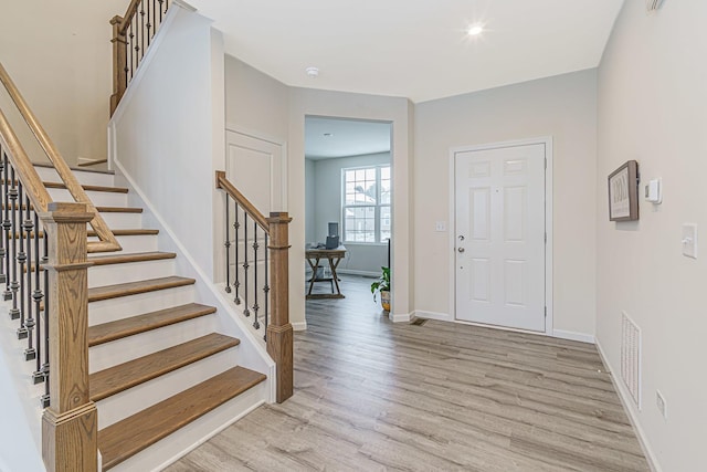 entryway with visible vents, light wood-style flooring, baseboards, and stairs