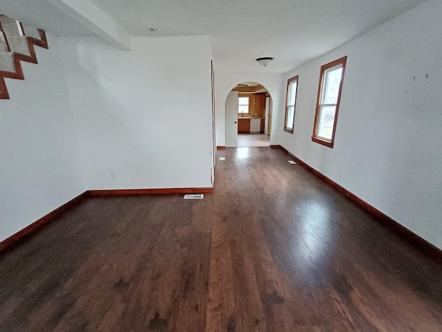 unfurnished room featuring beam ceiling and dark wood-type flooring