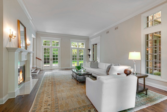 living room with wood-type flooring, french doors, a premium fireplace, and ornamental molding