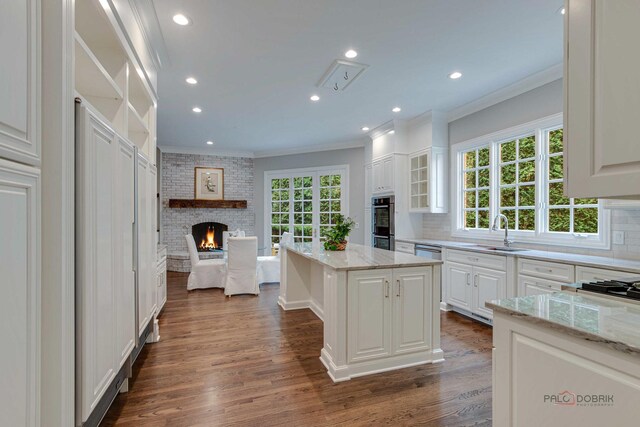 kitchen featuring a fireplace, tasteful backsplash, light stone counters, dark hardwood / wood-style floors, and a kitchen island