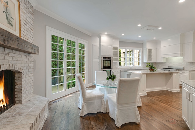 dining space with ornamental molding, sink, a fireplace, and hardwood / wood-style floors