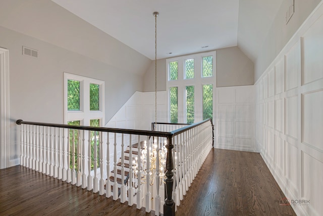 corridor featuring high vaulted ceiling, dark hardwood / wood-style floors, and a wealth of natural light