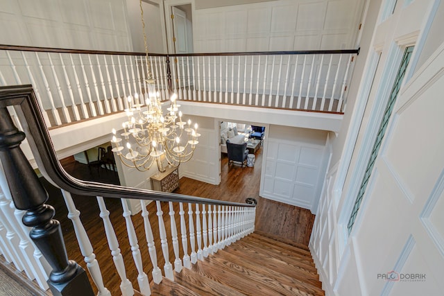 staircase featuring an inviting chandelier, hardwood / wood-style flooring, and a towering ceiling