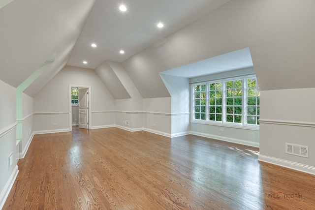 additional living space featuring wood-type flooring and vaulted ceiling