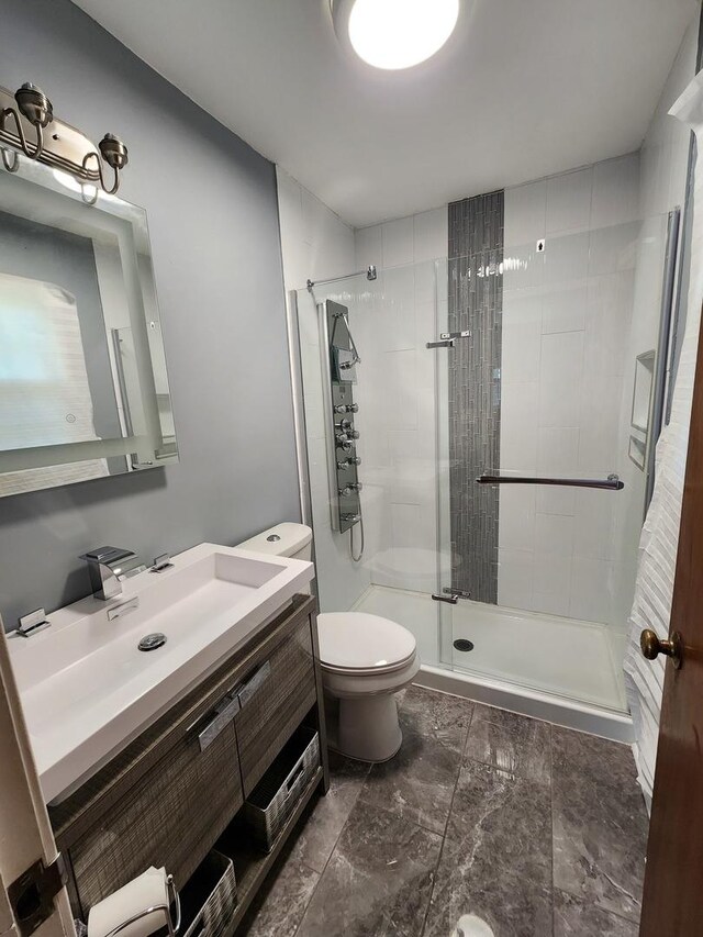 bathroom featuring vanity, toilet, a shower with door, and tile patterned flooring