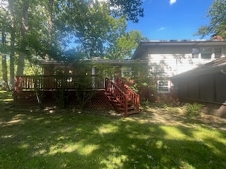 rear view of house featuring a wooden deck and a yard