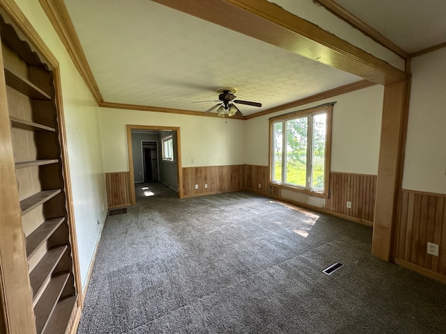 spare room featuring ceiling fan, dark carpet, and ornamental molding