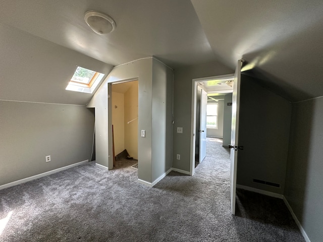 additional living space with vaulted ceiling with skylight and carpet flooring