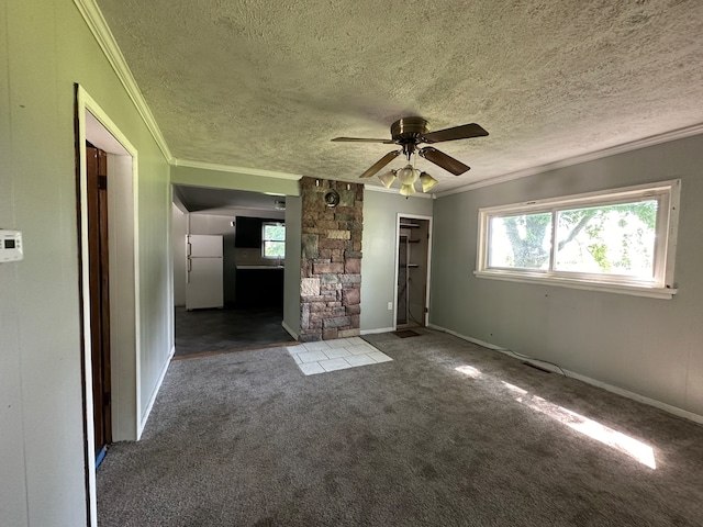 interior space with ceiling fan, dark carpet, a healthy amount of sunlight, and a textured ceiling