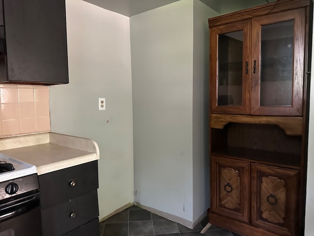 kitchen featuring tasteful backsplash, stove, and dark tile patterned floors