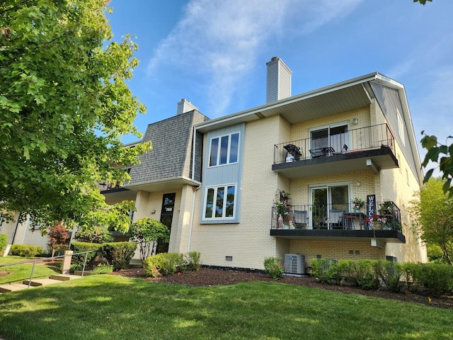 rear view of property with a lawn, central AC, and a balcony