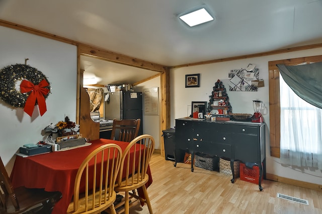 dining room with ornamental molding and light hardwood / wood-style flooring