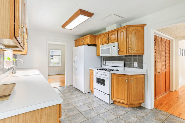 kitchen with sink, light hardwood / wood-style flooring, tasteful backsplash, and white appliances