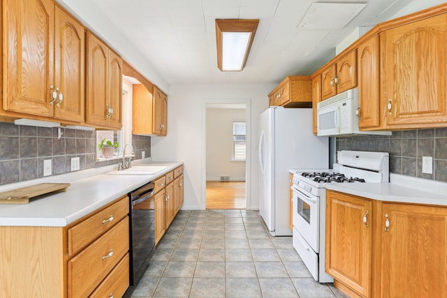 kitchen with decorative backsplash, sink, light wood-type flooring, and white appliances