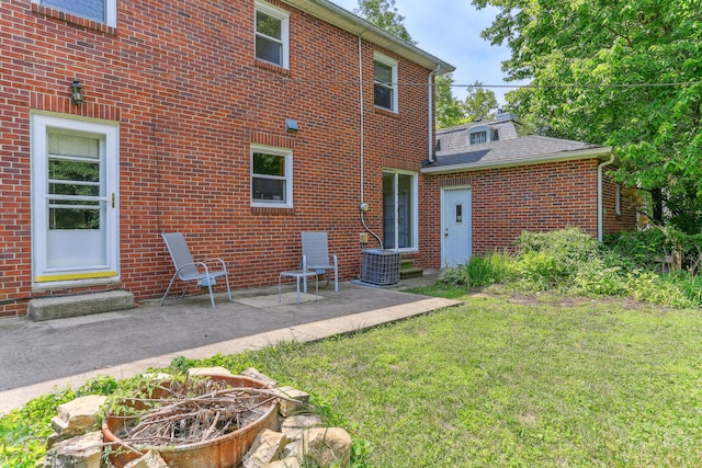 rear view of property with a patio, central air condition unit, and a yard