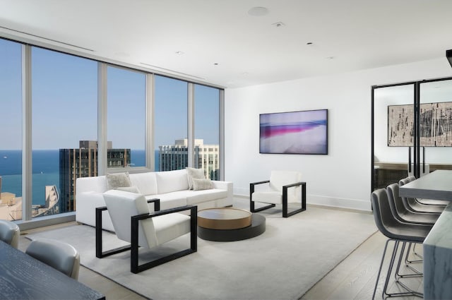 living room with a water view, light hardwood / wood-style flooring, and expansive windows