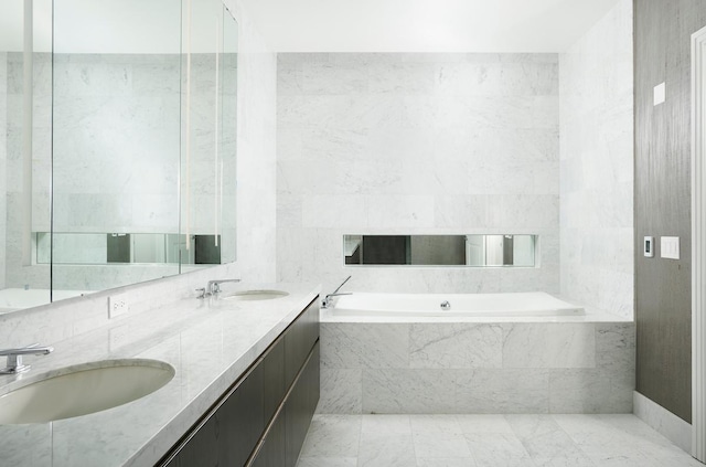 bathroom with vanity, tile walls, and a relaxing tiled tub