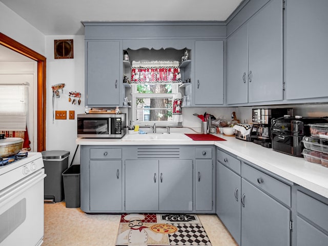 kitchen featuring sink, white range oven, and gray cabinetry